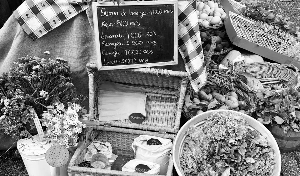 An outdoor market stall with flowers and produce.